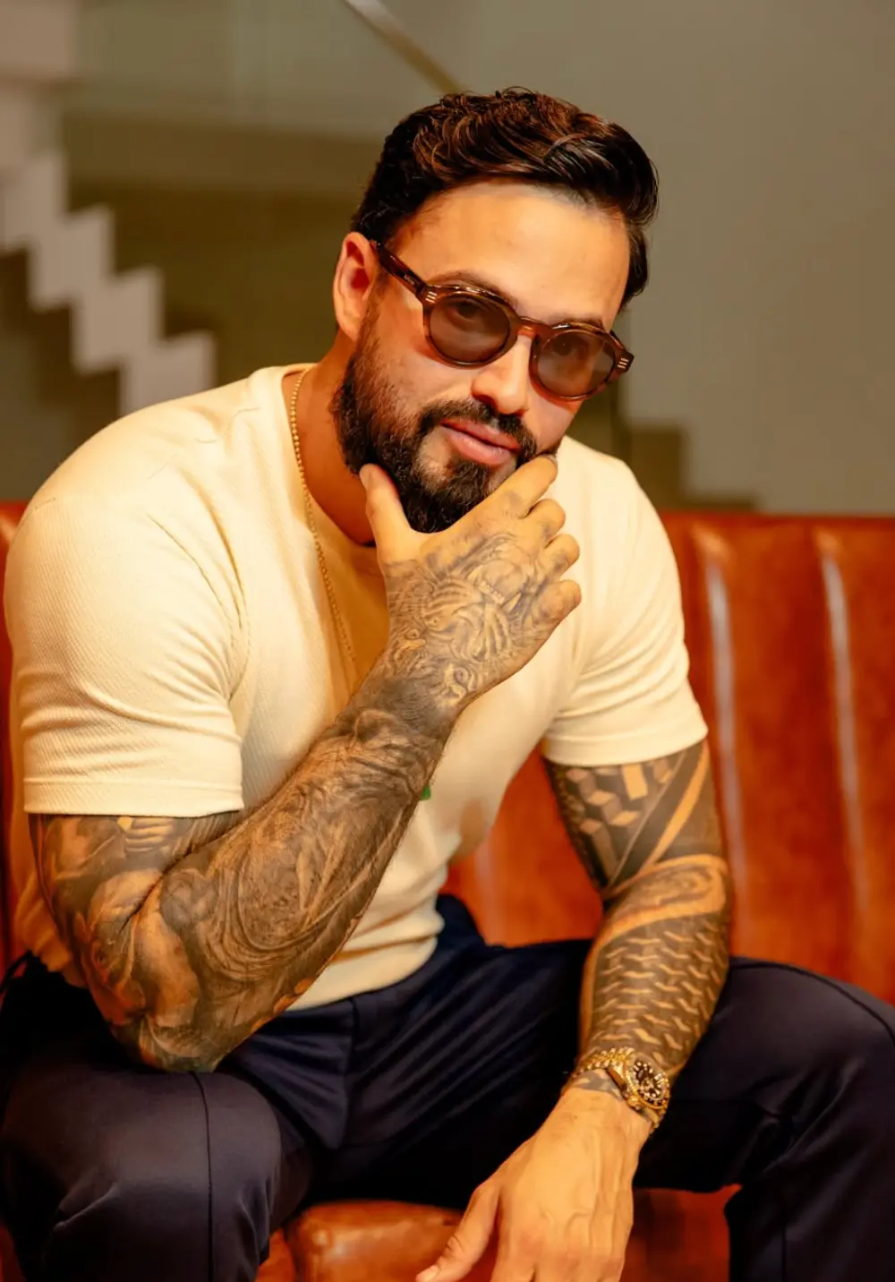 Gabriel Fernandes, tatoueur, assis sur un canapé en cuir